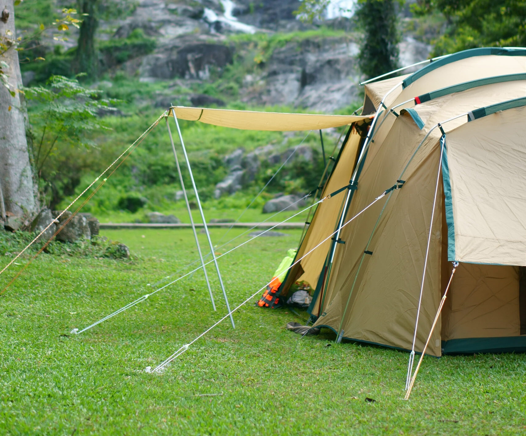 camping tent on waterfall and stream with tree in green jungle or forest for summer winter holiday relax and vacation travel trip with trekking and picnic on lawn or grass at Khlong Nam Lai Waterfall
