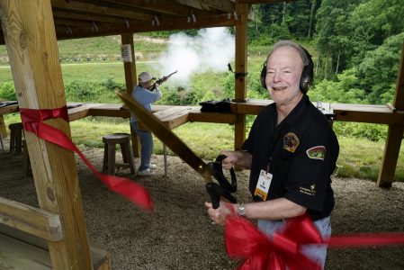 Si Brown cuts the dedication ribbon as Eaton Brown fires the ceremonial first shot at Si Brown's Rifle Range in 2018.