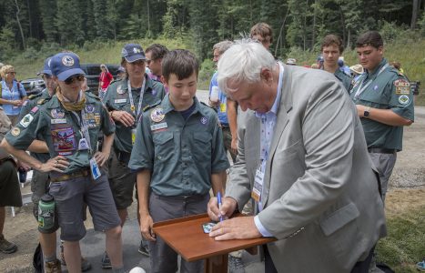West Virginia Governor Jim Justice autographs commemorative patches for the James C. Justice National Scout Camp while visiting with Scouts at the 2017 National Scout Jamboree.