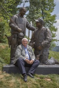 West Virginia Gov. Jim Justice rests at the bronze statue depicting him with his father.